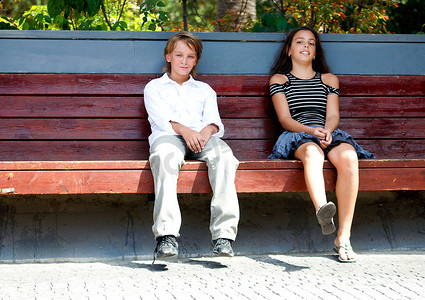 哈哈大笑卡通人物摄影照片_男孩和女孩坐在长凳上。
