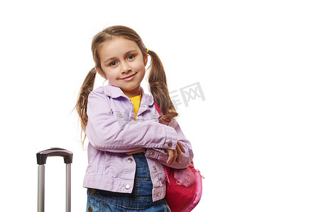 留着两条马尾辫的学龄前儿童可爱的小女孩，在白色背景下摆着粉色背包和手提箱。