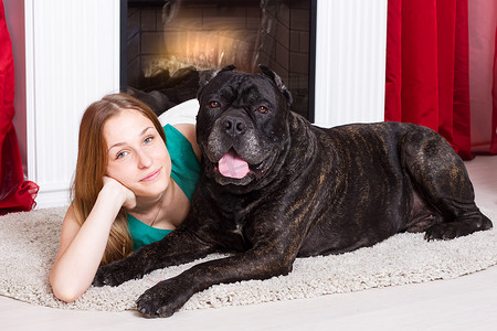 女孩和狗 Cane Corso 躺在壁炉旁