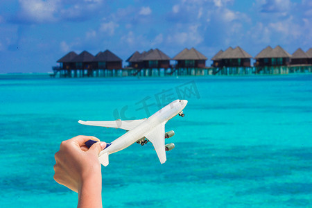 在热带海滩背景水上平房的小白色玩具飞机