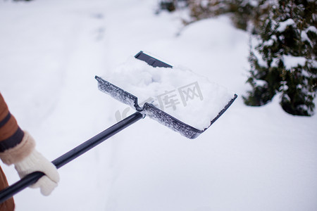 保暖衣物摄影照片_年轻女子的手从小路上铲雪的特写