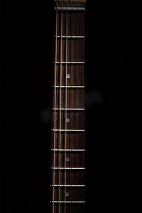 照亮黑暗摄影照片_从顶部照亮的吉他键盘
