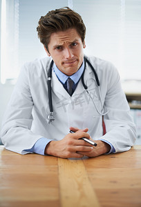 你的进步不如我们希望的那么好......一位严肃的年轻医生坐在他的办公桌前的肖像。