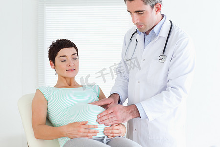 腹诊摄影照片_听诊孕妇肚子的医生