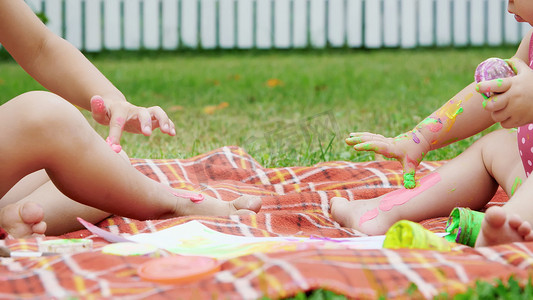 小孩，一个四岁的男孩和一个一岁的女孩，兄弟姐妹，一起玩耍，用手指画画，在花园里，坐在毯子上，在草地上，草坪上，在夏天