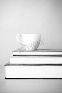 叠杯子摄影照片_一叠带咖啡杯黑白色调风格的书