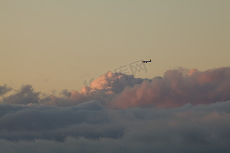 飞机夕阳摄影照片_日落时的飞机和低云
