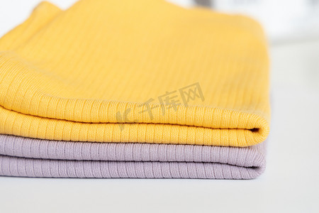 在白色背景隔离上堆叠折叠的紫色、黄色婴儿棉服。