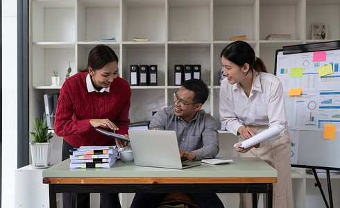 使用笔记本电脑在董事会会议桌上从事项目工作的多元化国际行政商务人士。