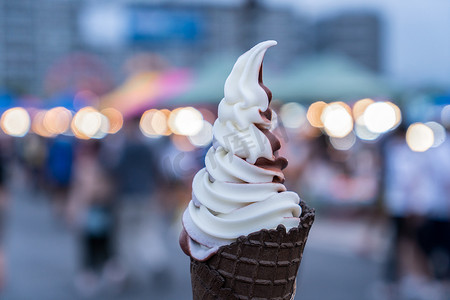 巧克力冰淇淋甜筒摄影照片_手拿着冰淇淋甜筒。