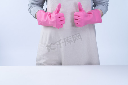 围裙的年轻女管家戴着粉色手套清洁桌子，预防病毒感染的概念，家政服务，特写。