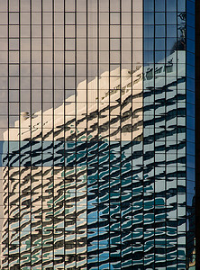 包角摄影照片_具有重复结构的建筑物玻璃墙上的天空和建筑反射。