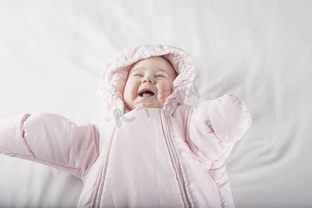 克蓝英蓝笑脸摄影照片_穿着粉红色雪衣的婴儿笑脸
