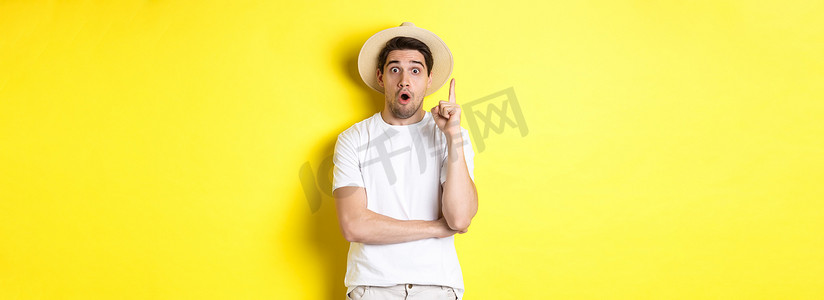 戴草帽的年轻人的肖像有想法，举起手指尤里卡标志，提出建议，站在黄色背景上