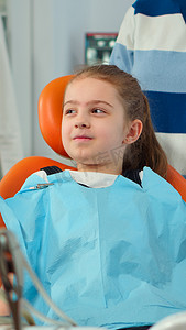 患牙痛的儿童患儿穿着牙科围嘴与牙医交谈的特写