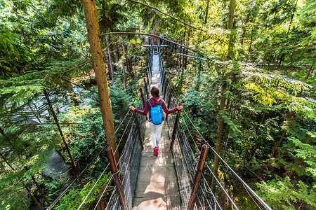 加拿大旅游女游客在不列颠哥伦比亚省北温哥华著名景点卡皮拉诺吊桥散步，加拿大旅游度假胜地