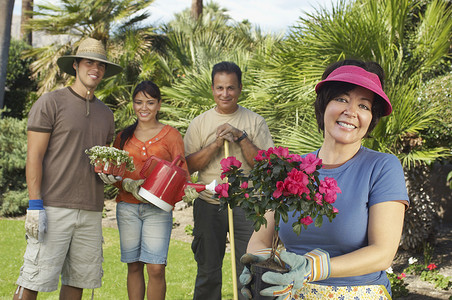 一个快乐的女人拿着花卉植物的肖像，家人站在背景中