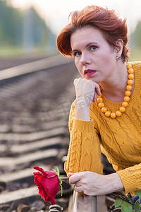 美丽的女人坐在铁路的轨道上与红玫瑰的肖像