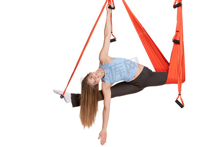 年轻女子在无缝白色背景的吊床上做反重力空中瑜伽。