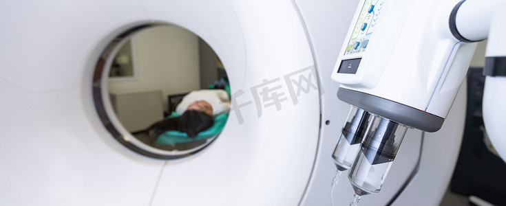 断层扫描仪摄影照片_CT 扫描技术专家在准备手术过程中俯瞰计算机断层扫描仪中的患者。