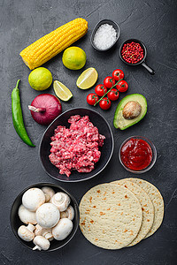 传统的墨西哥玉米饼，配料混合，玉米，肉，蔬菜，莎莎酱，黑色纹理背景，顶视图。