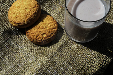 饼干酸奶摄影照片_饼干和一杯酸奶放在粗麻布材料上