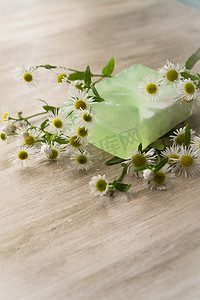 天然手工透明绿色肥皂和洋甘菊木制破旧背景上。