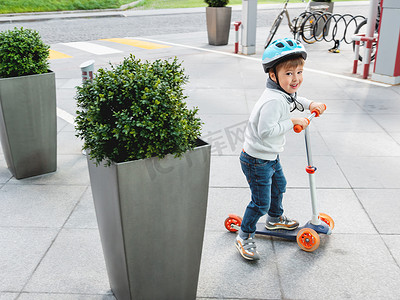 戴头盔的小孩在停车场骑滑板车，停着 b