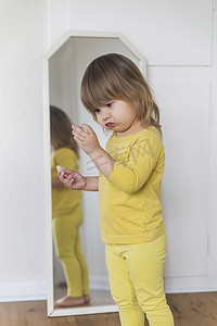 迷人的婴儿怀疑地检查镜子附近的一些小饰品