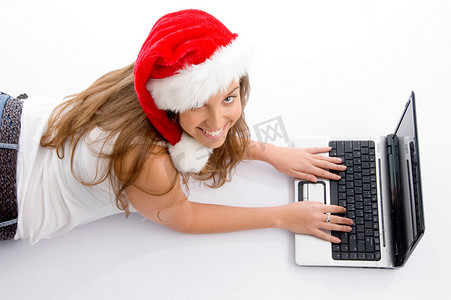 带着圣诞帽和笔记本电脑躺着的年轻女性