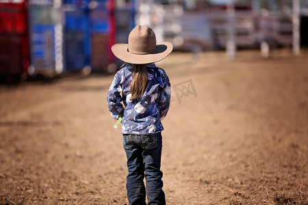 小女牛仔站在尘土中观看乡村牛仔竞技表演