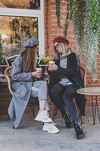 年轻女性最好的朋友在空闲时间互相交谈讨论有趣的主题嬉皮士女孩开玩笑和一起玩乐享受休闲与咖啡继续城市背景