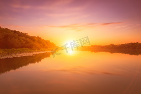 河上的日落或黎明，多云的天空和太阳光线反射在水、睡莲和沿岸生长的树木中。