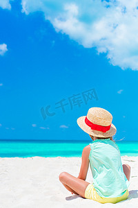 小孩海边摄影照片_海边沙滩上戴帽子的可爱小孩