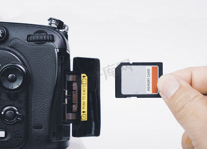 摄影师手插入存储 SD 卡到数码单反相机的存储槽，隔离在白色背景
