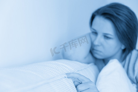 悲伤的女人坐在床上抱着枕头
