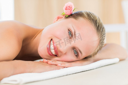 平和的金发女郎躺在毛巾上对着镜头微笑