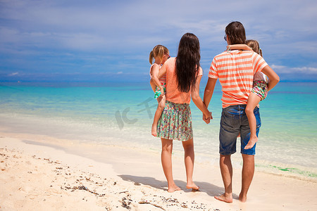 带两个孩子在热带度假的年轻美丽家庭的背影