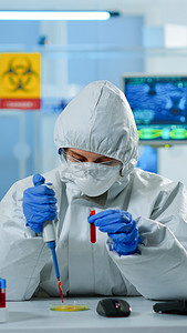 ppe 衣服的科学技术员使用微移液器和培养皿分析血样
