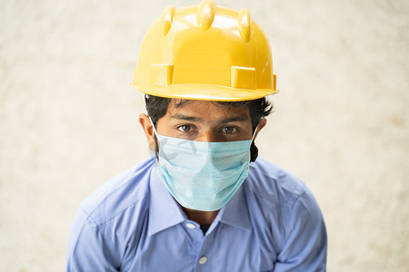 戴着医用口罩的建筑工人的兴视角自信地仰望 — 商业概念、行业重新开放和工作场所的 covid-19 安全措施。