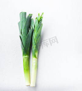 韭菜摄影照片_白桌上的绿色韭菜苏丹洋葱，顶视图。