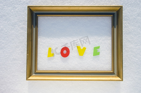 冬天艺术字摄影照片_雪上金色相框中的爱字。