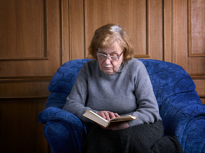 通用电气摄影照片_坐在扶手椅上拿着书的祖母