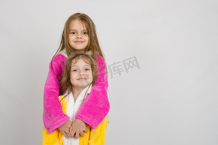 穿着浴袍摄影照片_穿着浴袍的女孩抱着她的妹妹穿着浴袍