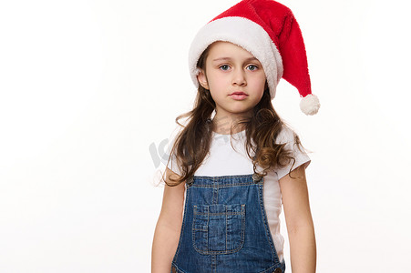 白色背景中一个戴着圣诞帽的漂亮可爱白人小女孩的肖像，期待圣诞假期
