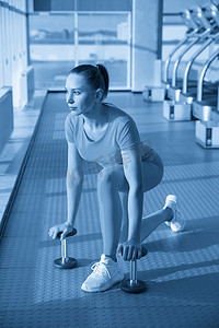 健身房里身体健康的女人带着哑铃准备加强她的手臂和二头肌