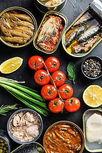 罐头罐装食品罐装新鲜有机生物成分西红柿香草柠檬准备的蔬菜、肉、鱼和水果在黑色黑板上的锡罐中。