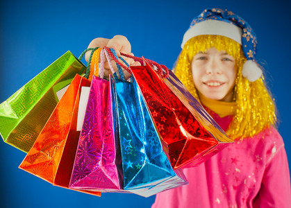 购物狂欢蓝色摄影照片_蓝色背景下，少女拿着各种彩色袋子