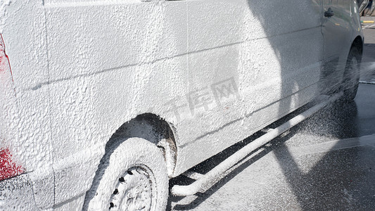 汽车在洗车场，用肥皂泡沫洗车，特写。洗掉卡车上的污垢。