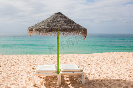 沙滩躺椅遮阳伞摄影照片_沙漠海岸异国情调度假村的沙滩躺椅和遮阳伞